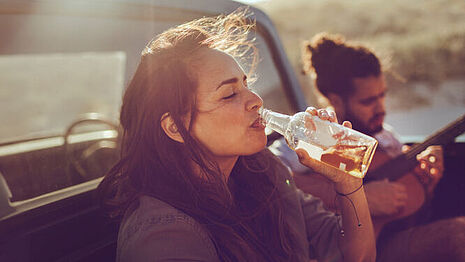 Una mujer bebe una botella de cerveza