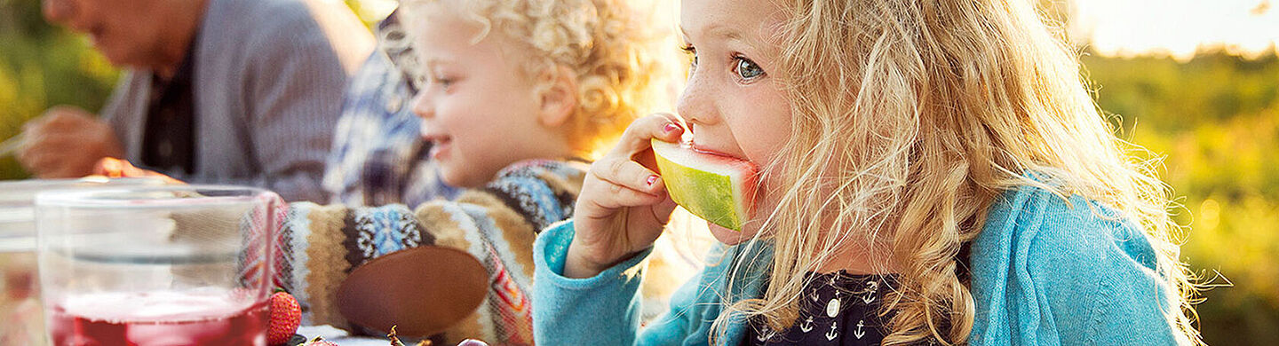 crianças em uma mesa comendo melancia