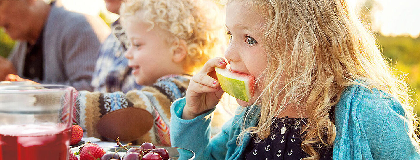 Kinder auf einem Tisch, die Wassermelone essen