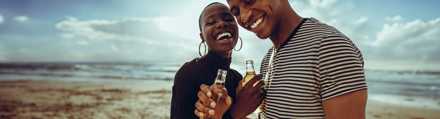 Una mujer y un hombre sostienen botellas de cerveza en la mano.