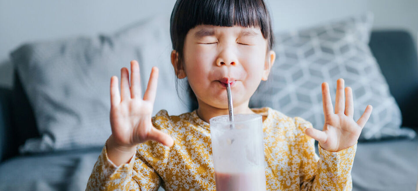 menina bebendo leite de um canudo