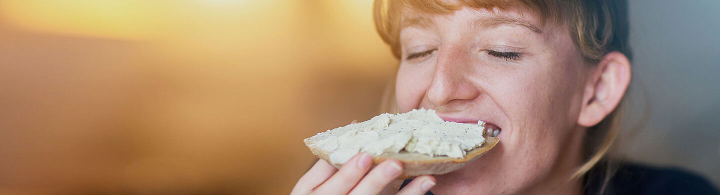 Mujer comiendo una rebanada de pan con pasta