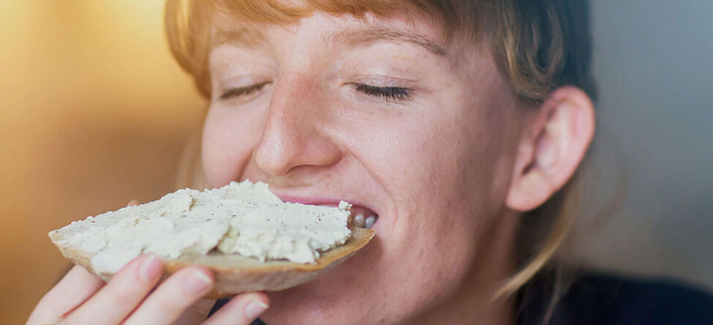 Mujer comiendo una rebanada de pan con pasta