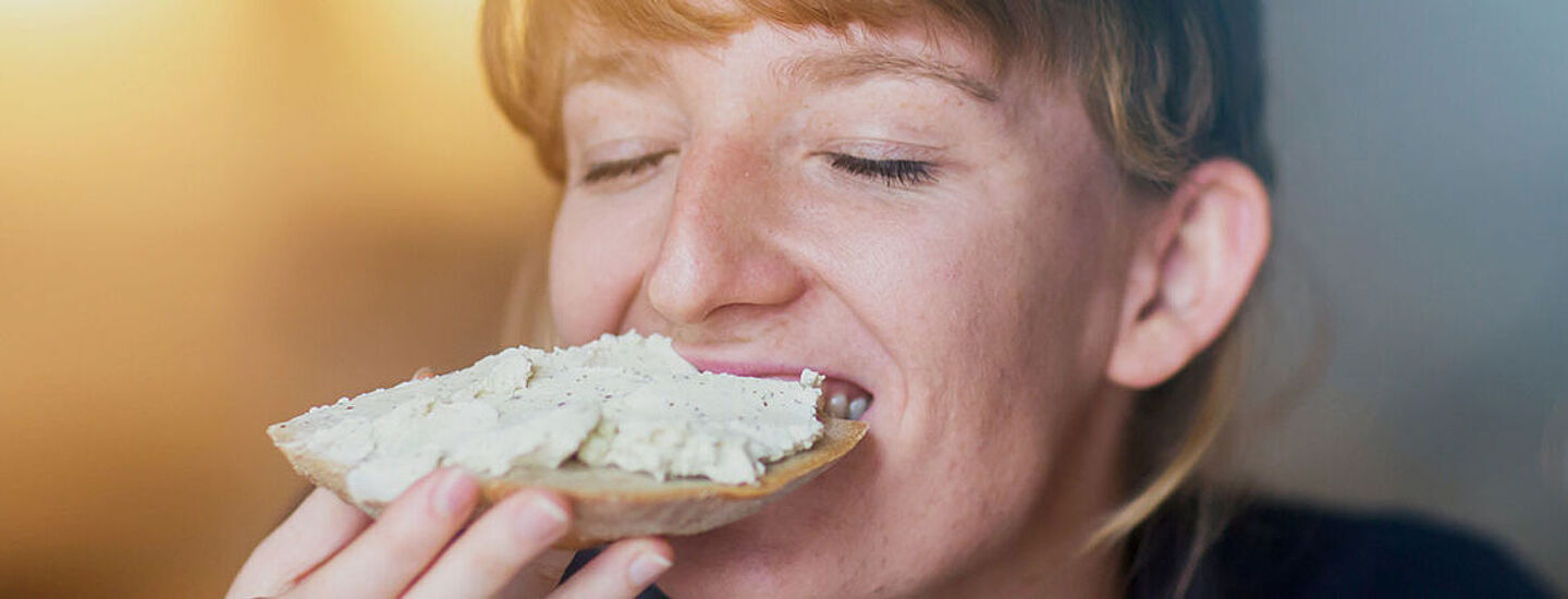 Mujer comiendo una rebanada de pan con pasta