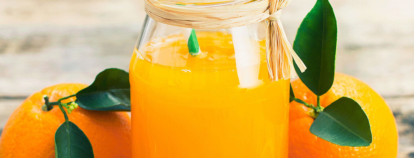 Orangensaft mit Orange im Hintergrund