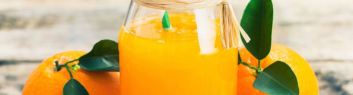 Orangensaft mit Orange im Hintergrund