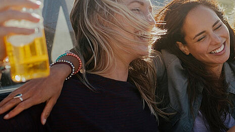 Duas meninas estão sorrindo e bebendo sidra