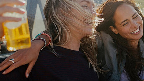 Two girls are smiling and drinking cider