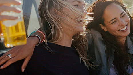 Zwei Mädchen lächeln und trinken Cider