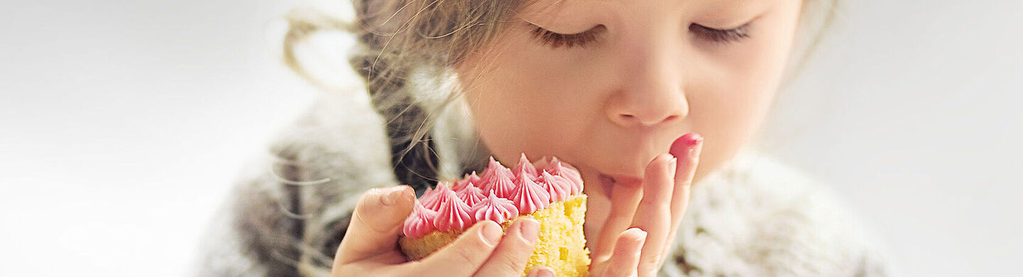little girl eating a cake with a pink topping
