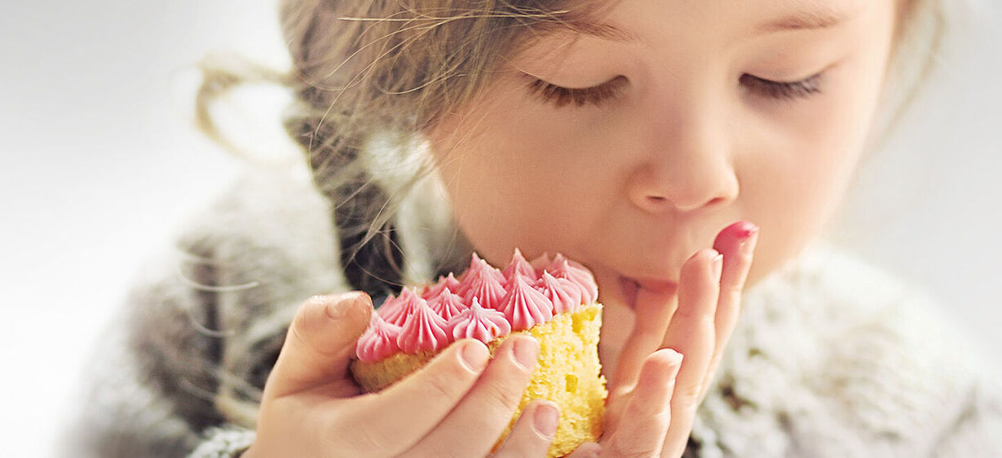 little girl eating a cake with a pink topping