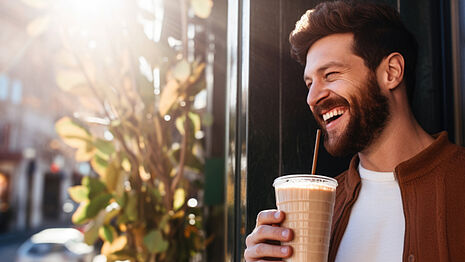 Ein lächelnder Mann mit einer Tasse Kaffee