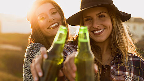 Zwei Mädchen lächeln und trinken Cider