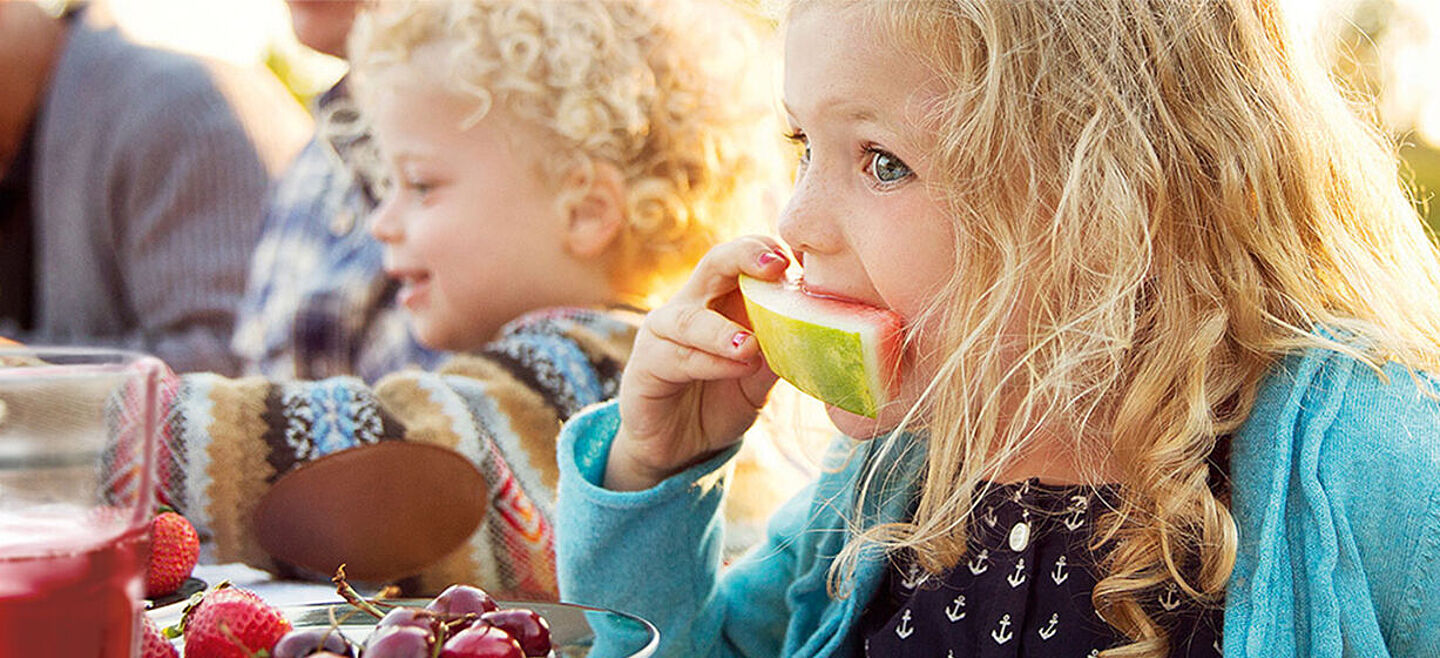 Kinder auf einem Tisch, die Wassermelone essen