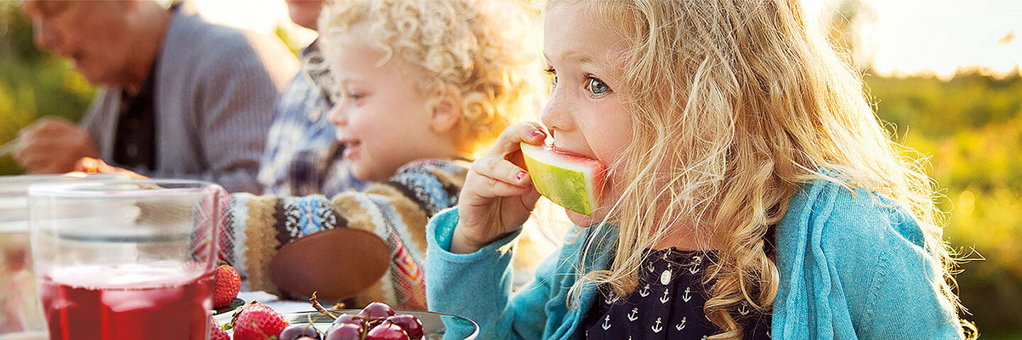 Kinder auf einem Tisch, die Wassermelone essen