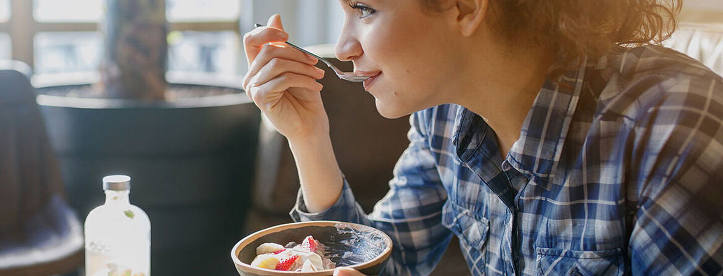 young woman eats a dessert with a spoon