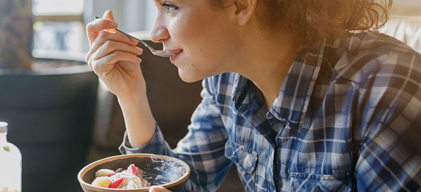 young woman eats a dessert with a spoon