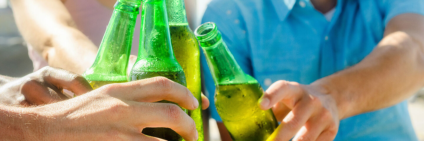 friends cheering with beer on green bottles