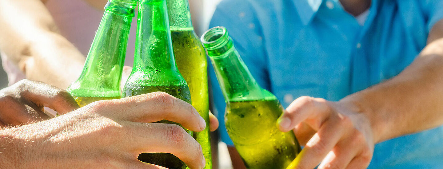 friends cheering with beer on green bottles