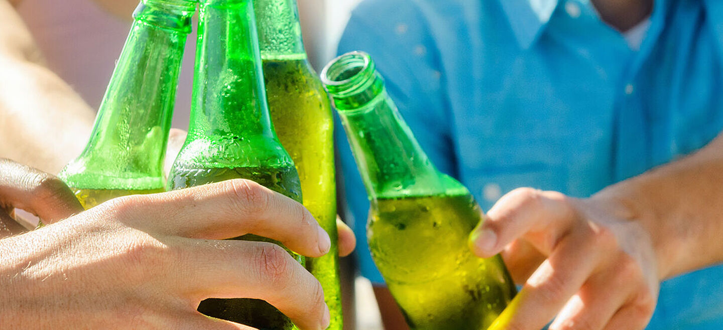 Freunde stoßen mit Bier in grünen Flaschen an