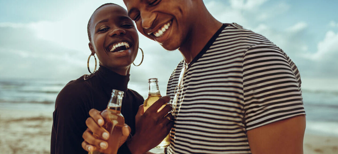 A woman and a man are holding beer bottles in their hand 