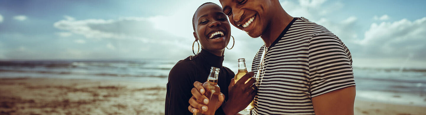 A woman and a man are holding beer bottles in their hand 