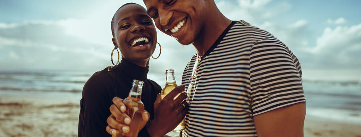 A woman and a man are holding beer bottles in their hand 