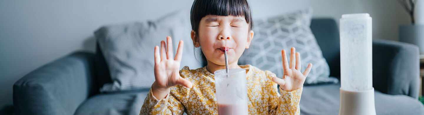 El niño bebe leche con una pajita