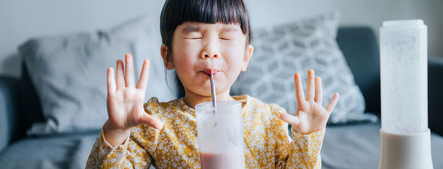 El niño bebe leche con una pajita
