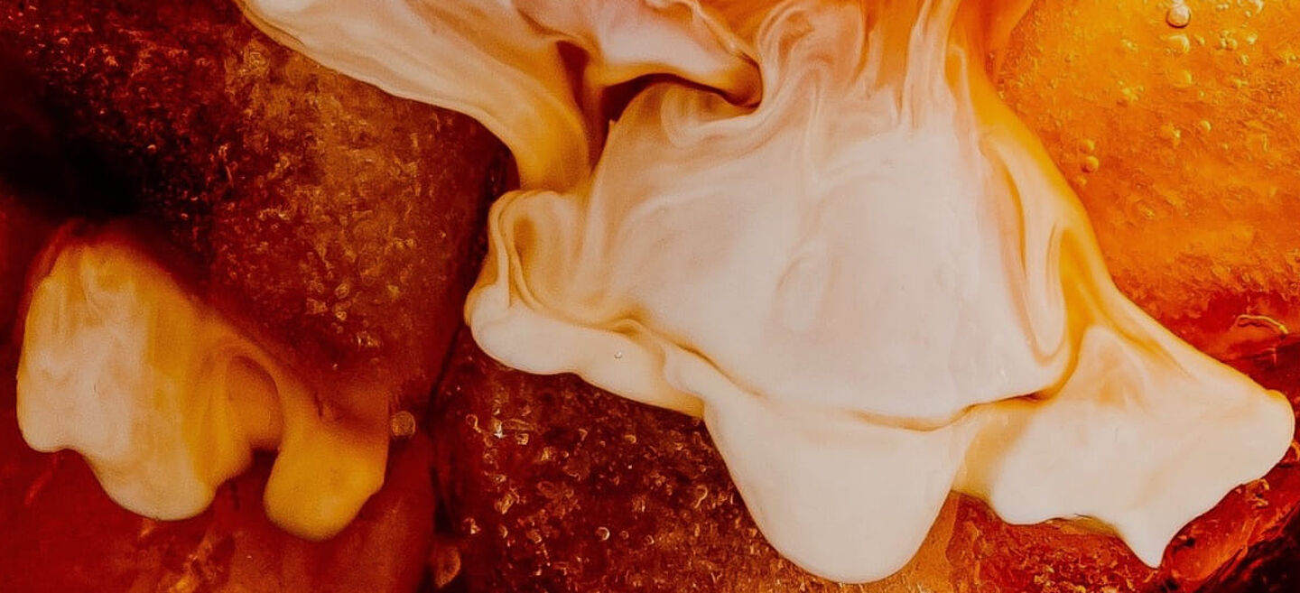 Buzlu kahve ve kremalı sütün kahve sıvısında dağıldığı yakın çekim.