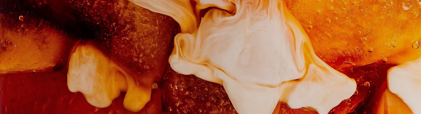 Buzlu kahve ve kremalı sütün kahve sıvısında dağıldığı yakın çekim.