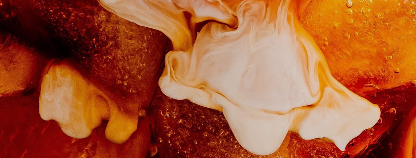 Buzlu kahve ve kremalı sütün kahve sıvısında dağıldığı yakın çekim.