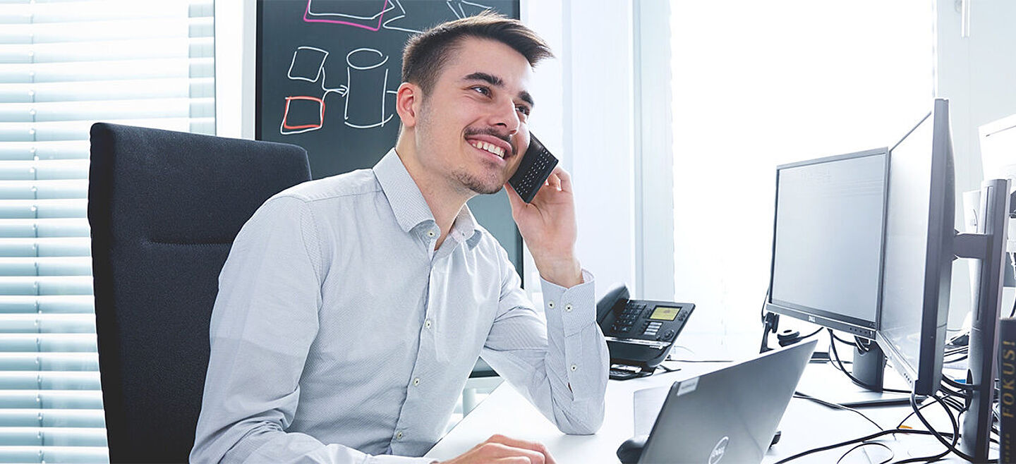 Mann auf einem Schreibtisch, der ein Telefongespräch führt