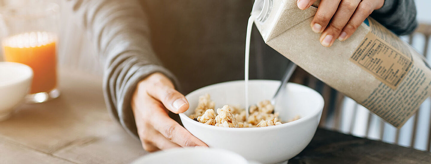 Mann gibt Milch in eine Müslischale