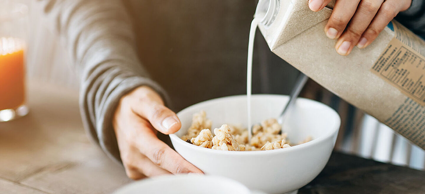 Mann gibt Milch in eine Müslischale