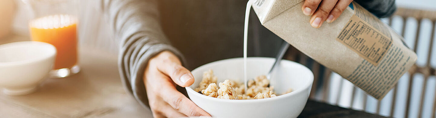 man putting milk in a bowl of cereals