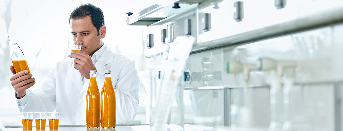 Científicos con frascos de líquido naranja y muestras.