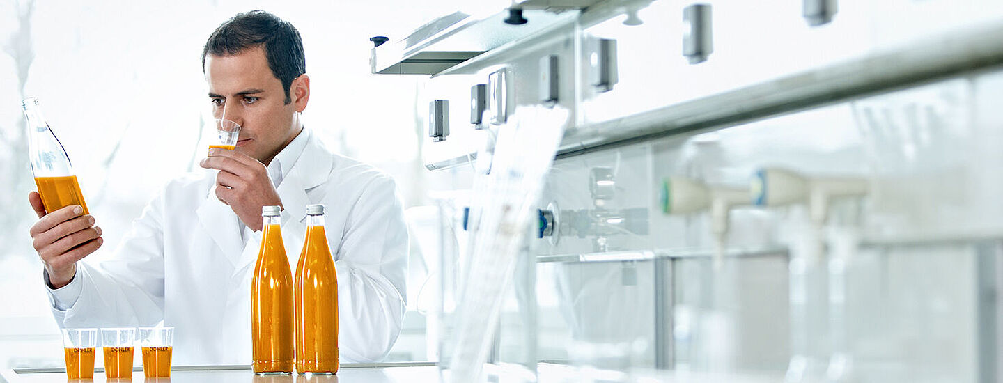 scientist with bottles with orange liquid and samples