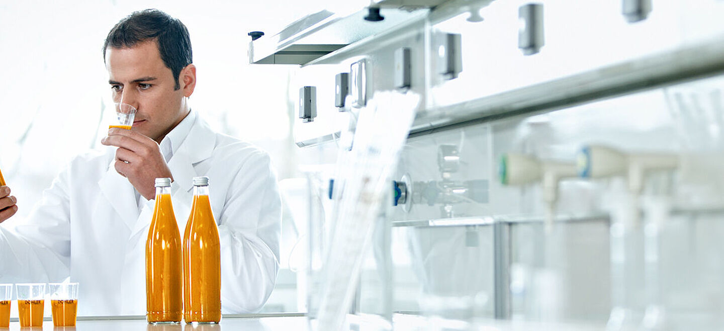 Wissenschaftler mit Flaschen mit orangefarbener Flüssigkeit und Proben