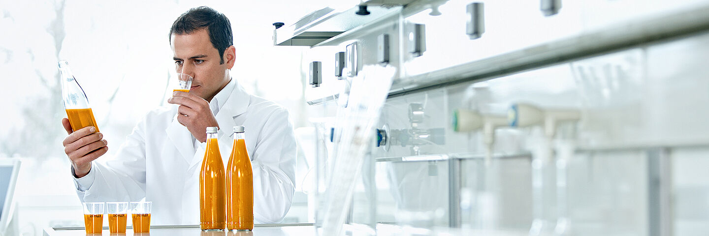 scientist with bottles with orange liquid and samples