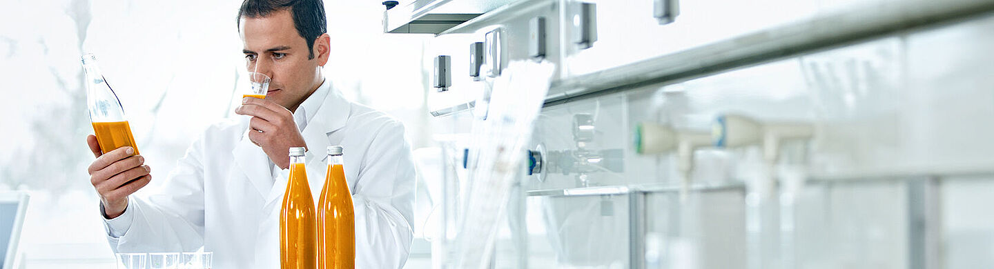 scientist with bottles with orange liquid and samples