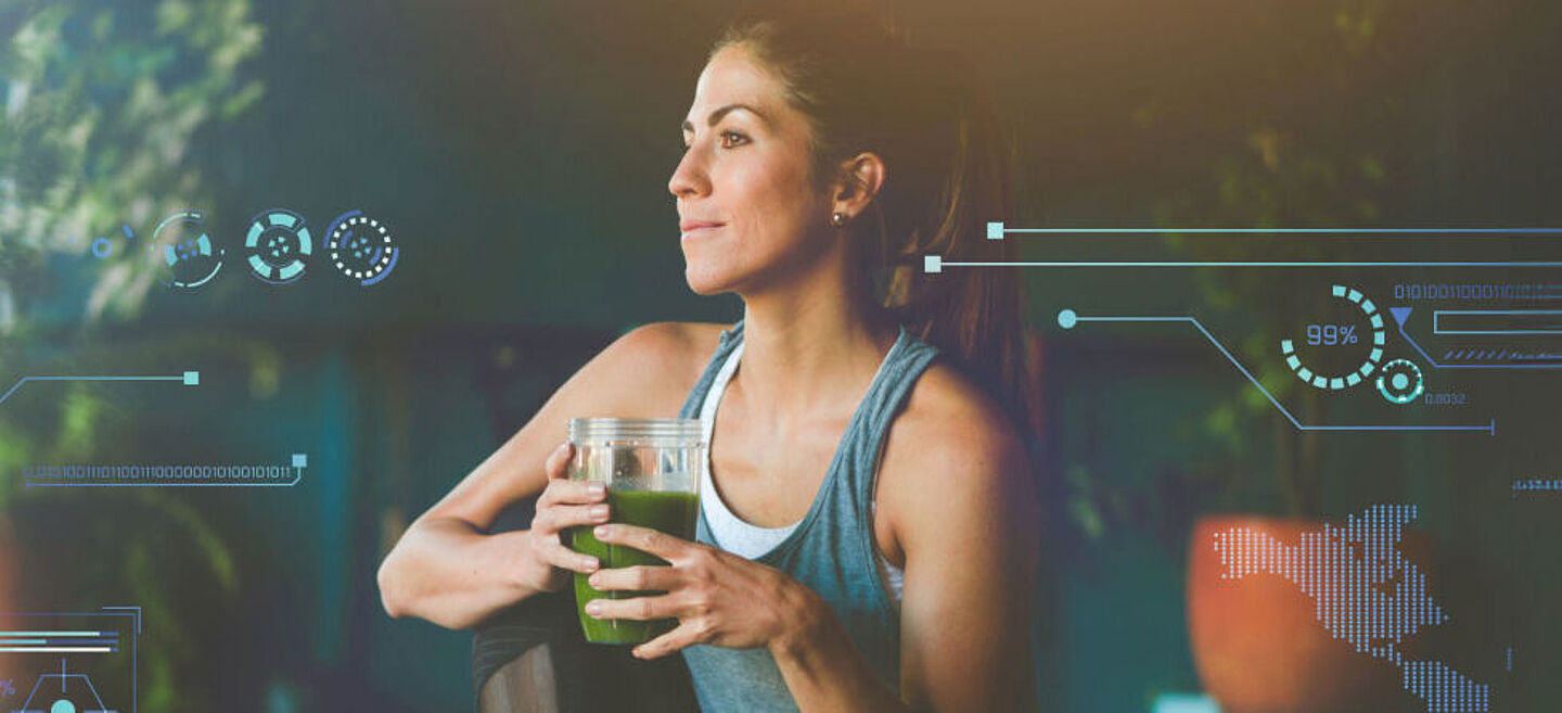 Woman in sportswear holding a green smoothie in her hand