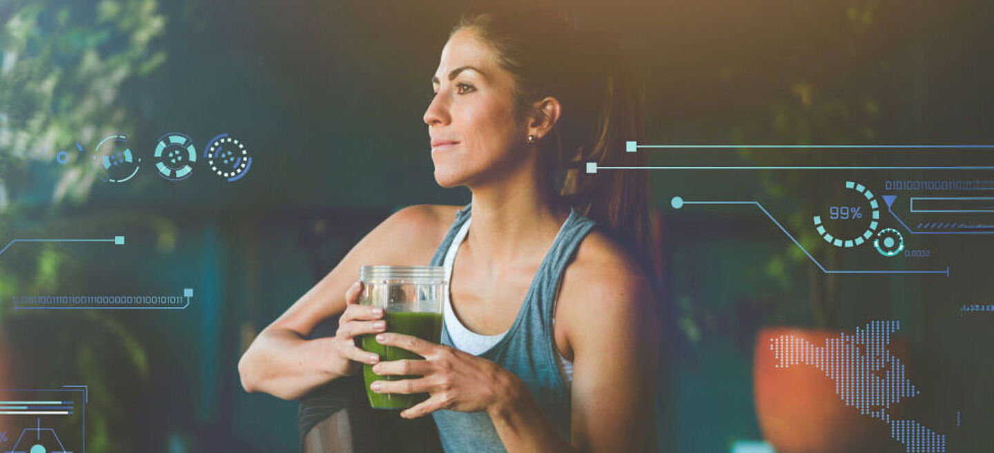 Mulher em roupas esportivas segurando um smoothie verde na mão