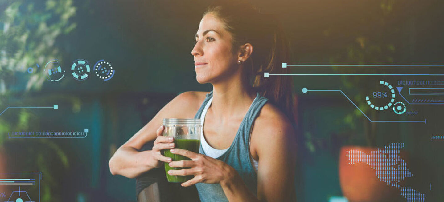 Frau in Sportkleidung mit einem grünen Smoothie in der Hand