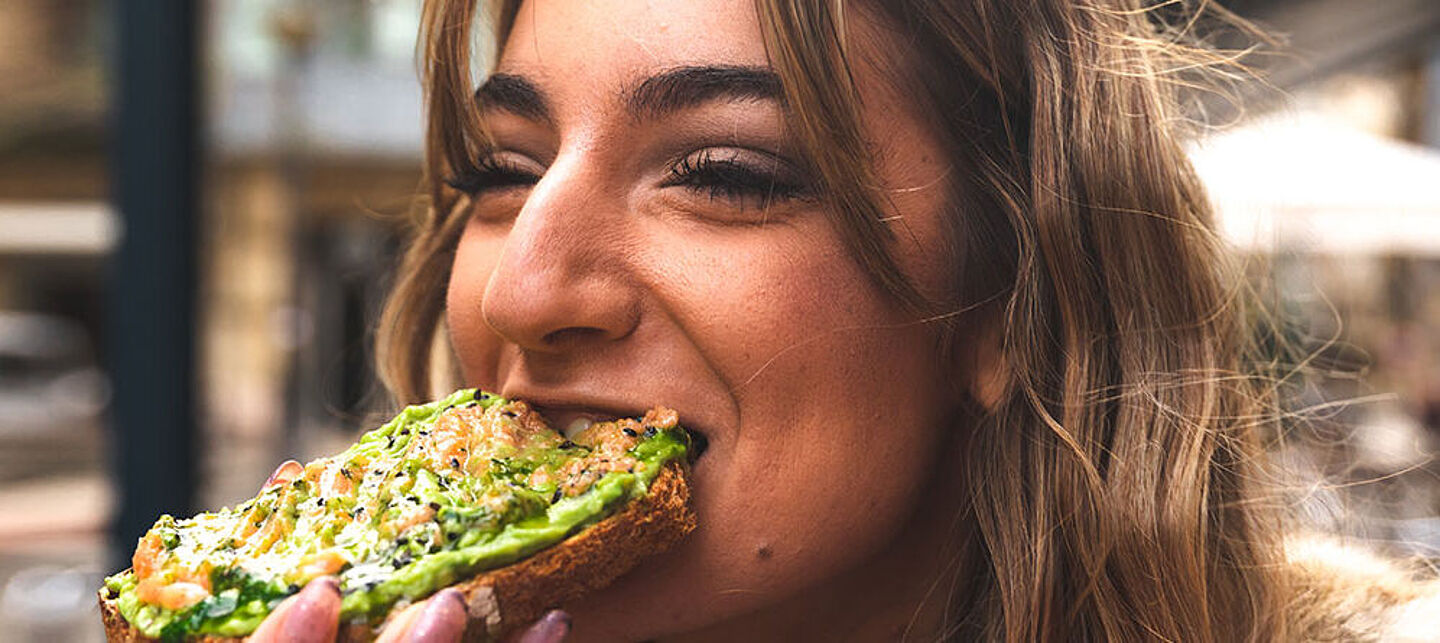 lady eating a bread with a cheese spread