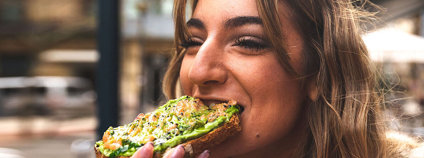 lady eating a bread with a cheese spread